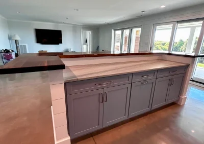 Kitchen island with gray cabinets, double countertops, and open living space in the background.