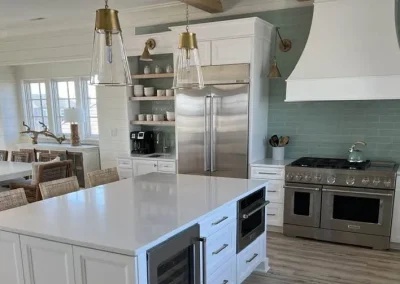 Modern kitchen with white cabinets, an island, stainless steel appliances, and a dining area.