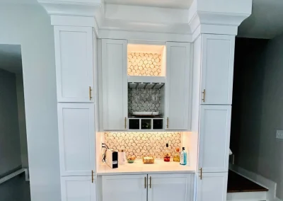 White built-in kitchen cabinets with gold handles and a lit backsplash featuring a honeycomb tile pattern.