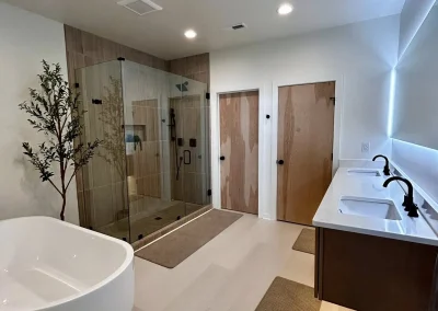 Modern bathroom with a freestanding tub, glass shower, double sinks, and wood accents.