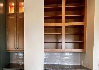 Built-in desk with blue drawers, wooden shelves, cabinets, and a white column dividing the workspace.