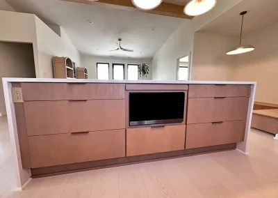 Modern kitchen island with wooden drawers and a built-in black microwave, under pendant lights.