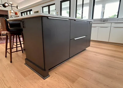 Modern kitchen island with dark cabinetry, light wood flooring, and a countertop in a bright open space.