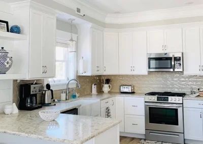 Bright kitchen with white cabinets, marble countertop, stainless appliances, and decorative accents.
