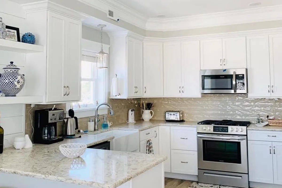 Bright kitchen with white cabinets, marble countertop, stainless appliances, and decorative accents.