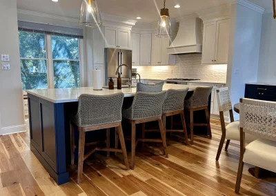 Modern kitchen with a large island, wicker bar stools, pendant lights, and wood floors.
