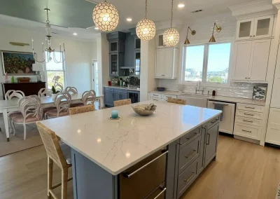 Modern kitchen with marble island, pendant lights, and dining area in the background.