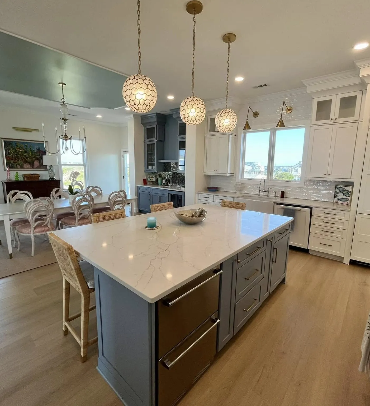 Modern kitchen with marble island, pendant lights, and dining area in the background.
